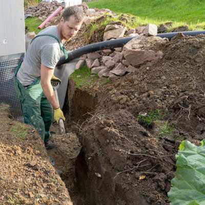 image of a man digging a trench for choosing a herringbone drainage system blog